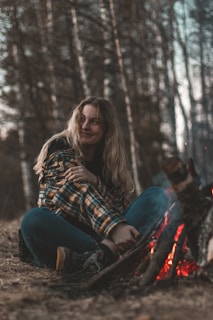 woman in blue denim jeans sitting on ground beside brown dog during daytime