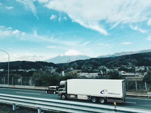 A move transport service truck driving along a scenic highway with mountains in the background.