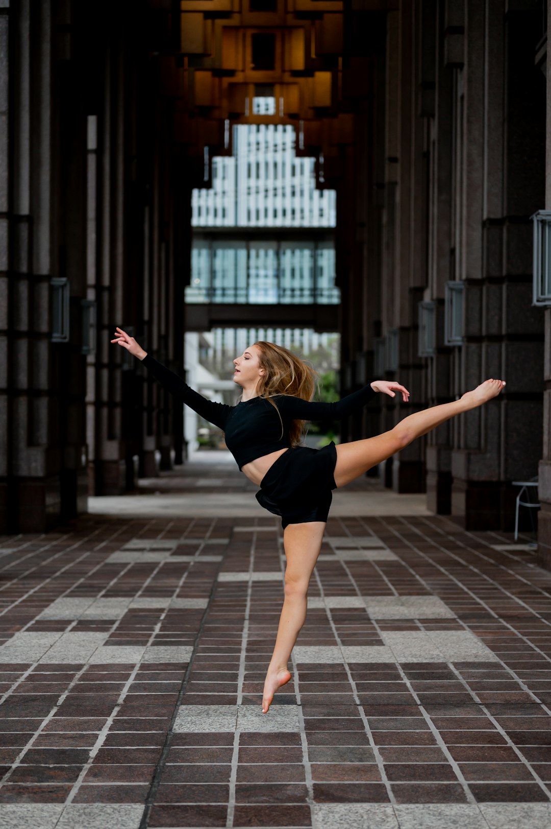 woman in black tank top and black shorts jumping on gray brick floor