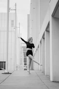 A black and white photograph of a ballerina mid-leap in an urban setting.