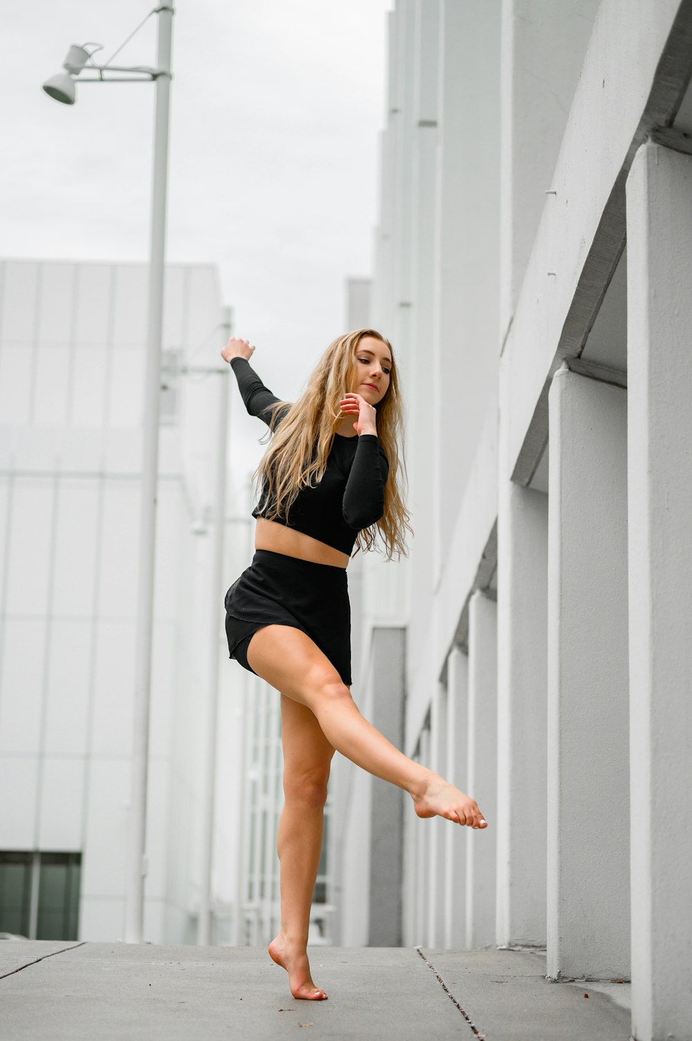 woman in black crop top and black shorts standing beside white wall during daytime