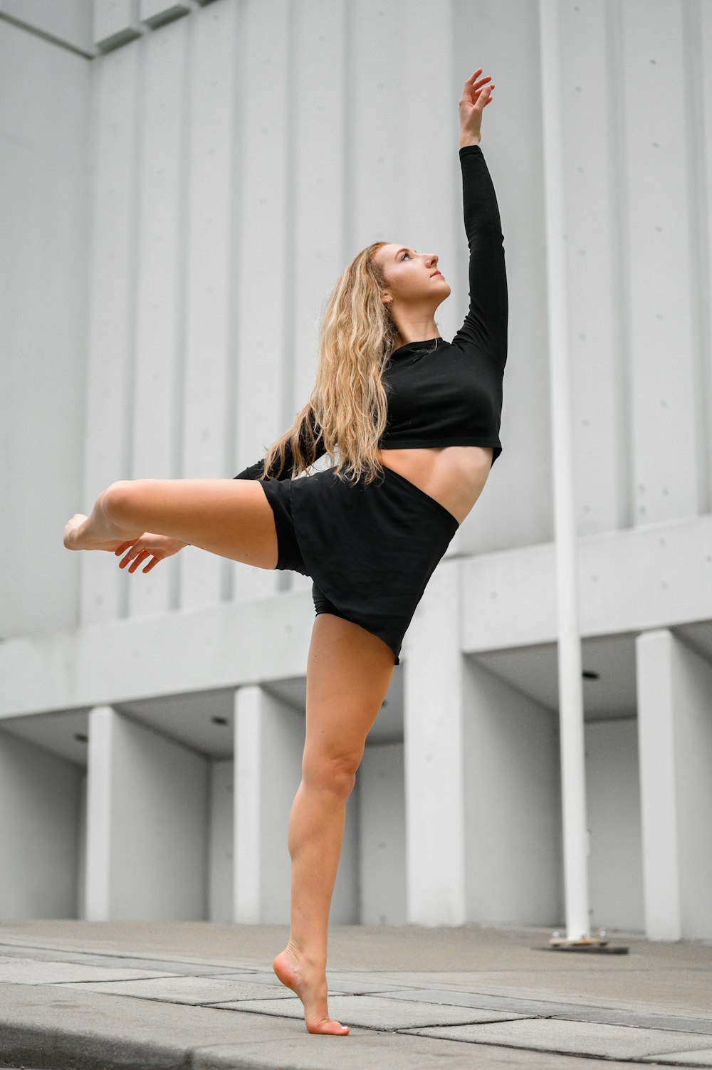 woman in black shirt and black shorts standing near white wall