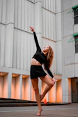 Urban lifestyle scene with a dancer in Lumina’s flowy activewear striking a dynamic pose on concrete steps