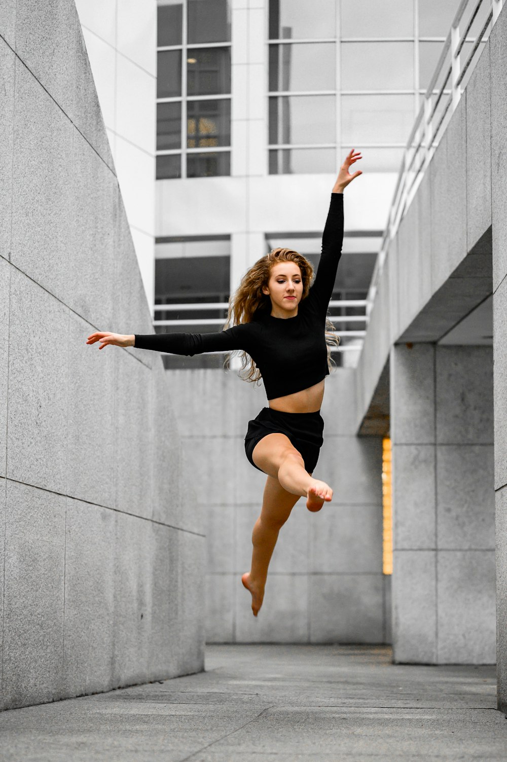 Foto Mujer con camiseta negra y pantalones cortos naranjas saltando sobre  una pared de hormigón gris durante el día – Imagen Ballet gratis en Unsplash