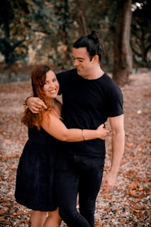 man in black crew neck t-shirt hugging woman in black dress