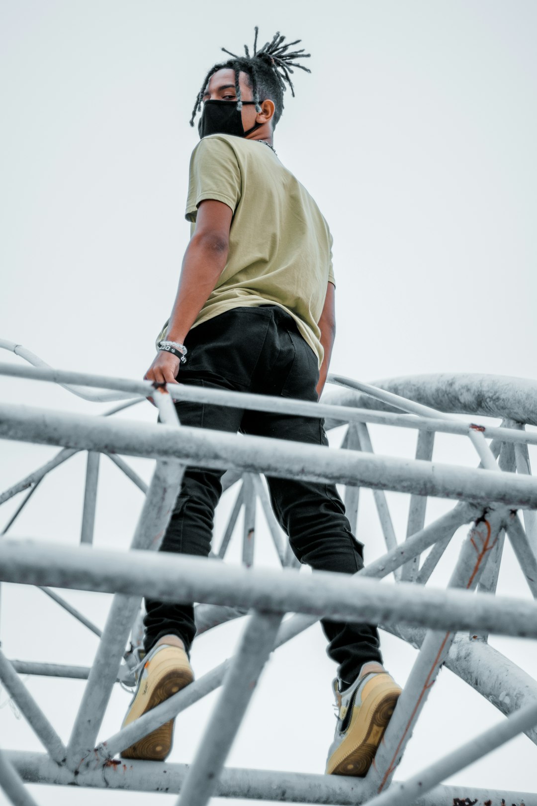 man in yellow shirt and black pants climbing on gray metal ladder during daytime