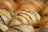 Golden, flaky pastries drizzled with dark chocolate are arranged in close proximity. The pastries have a delicate, layered texture that is visually appetizing.