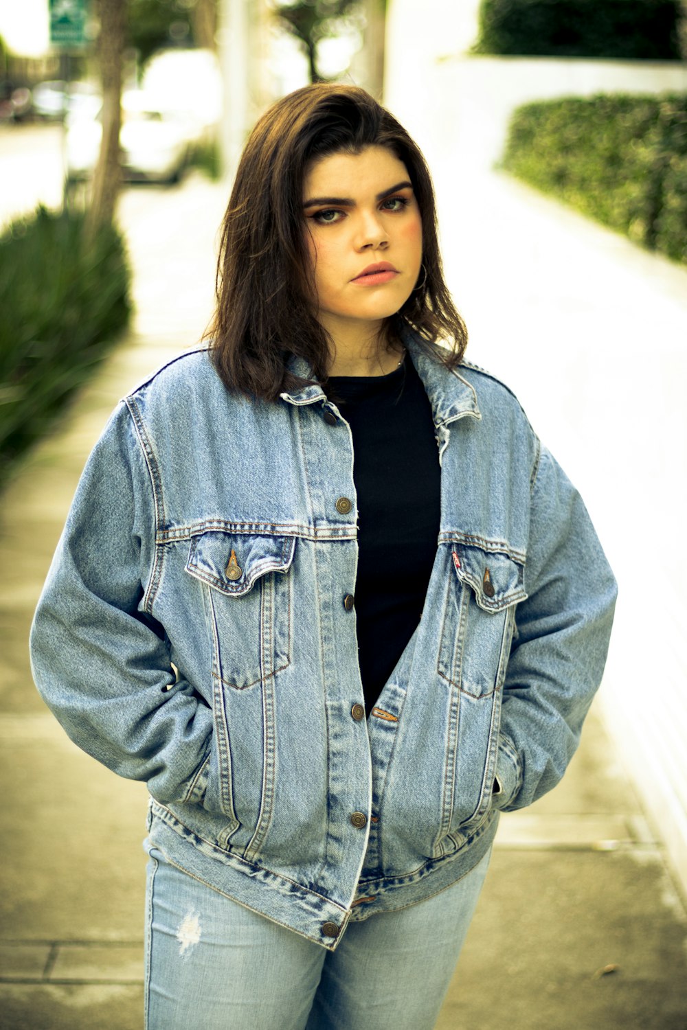 woman in blue denim jacket standing on road during daytime