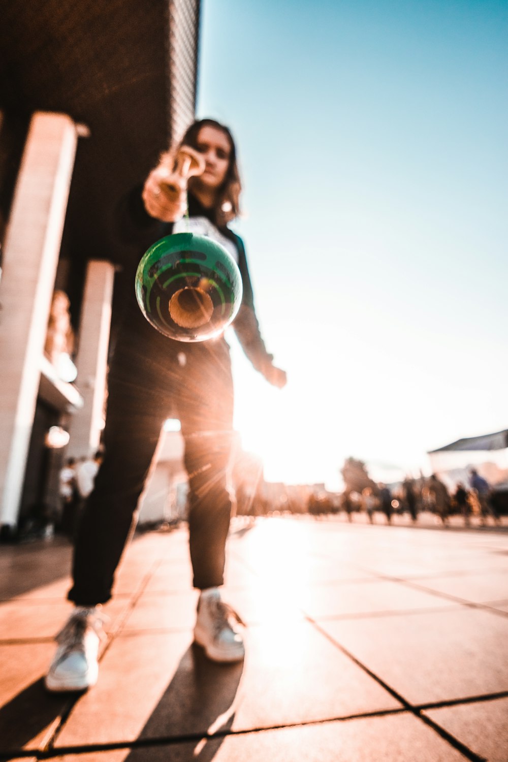 woman in gray shirt and pants holding green and blue ball