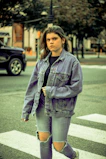 Model wearing a full denim outfit walking through a bustling city street.