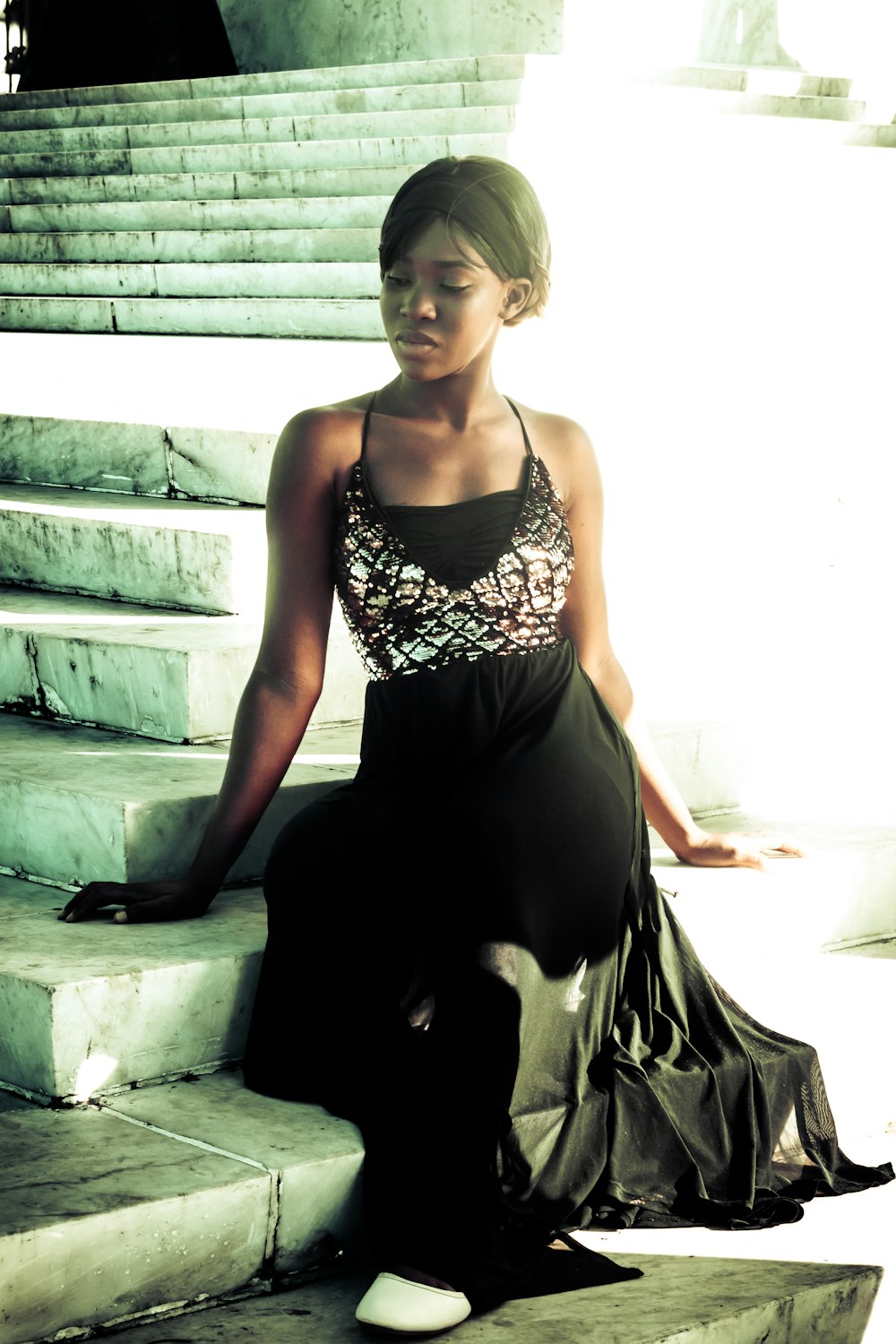 woman in black and white floral spaghetti strap dress sitting on concrete stairs