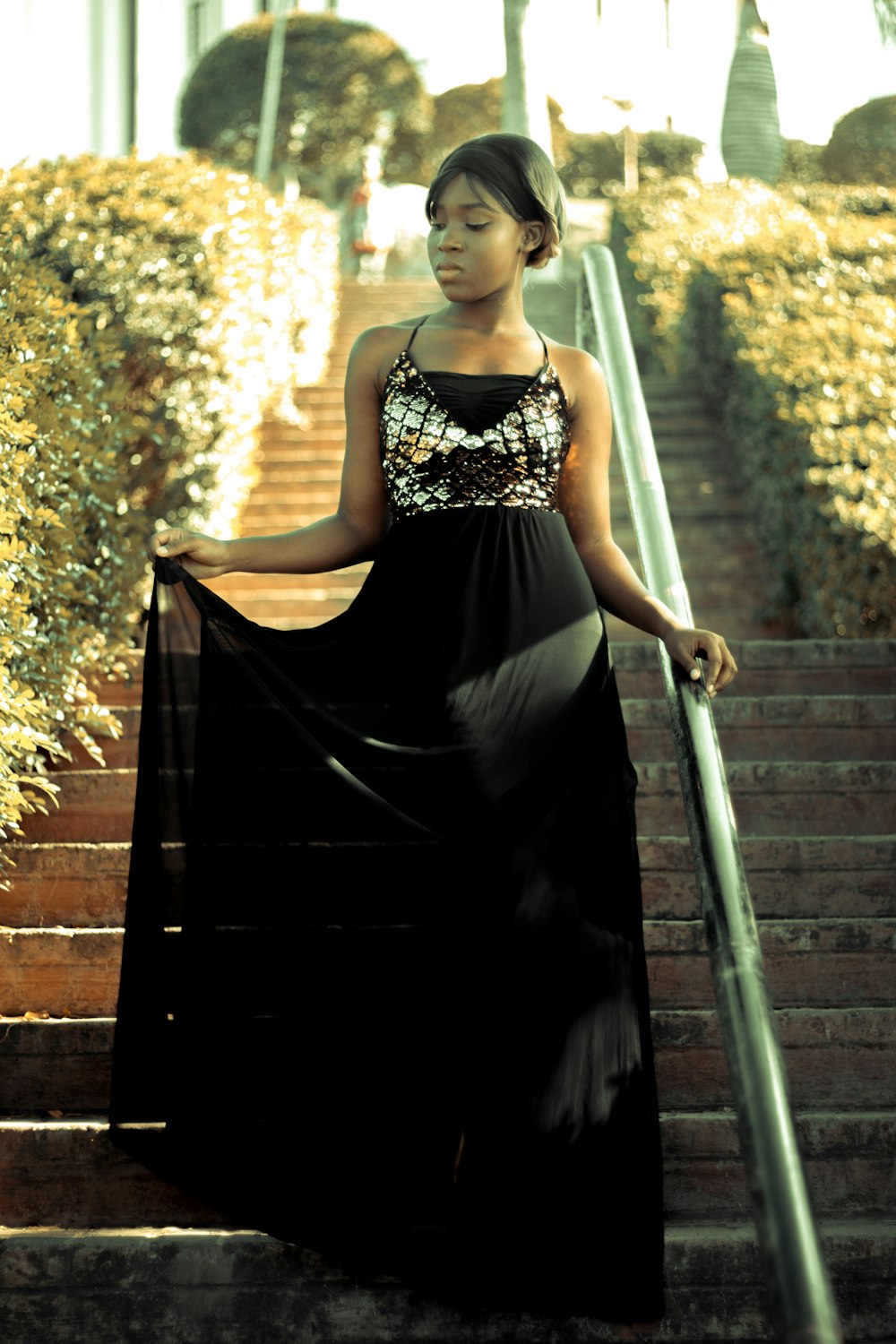 woman in black and white floral spaghetti strap dress standing on stairs