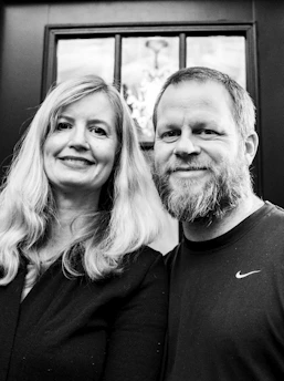 A smiling couple posing in a magazine-style photobooth with glossy printouts.