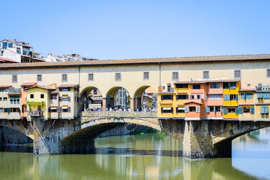 brown concrete building near river during daytime in Ponte Vecchio Italy