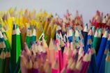 A close-up of vibrant colored pencils scattered over an open coloring book page filled with floral patterns.