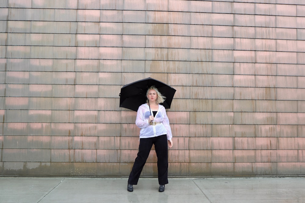 woman in white long sleeve shirt and black pants holding umbrella