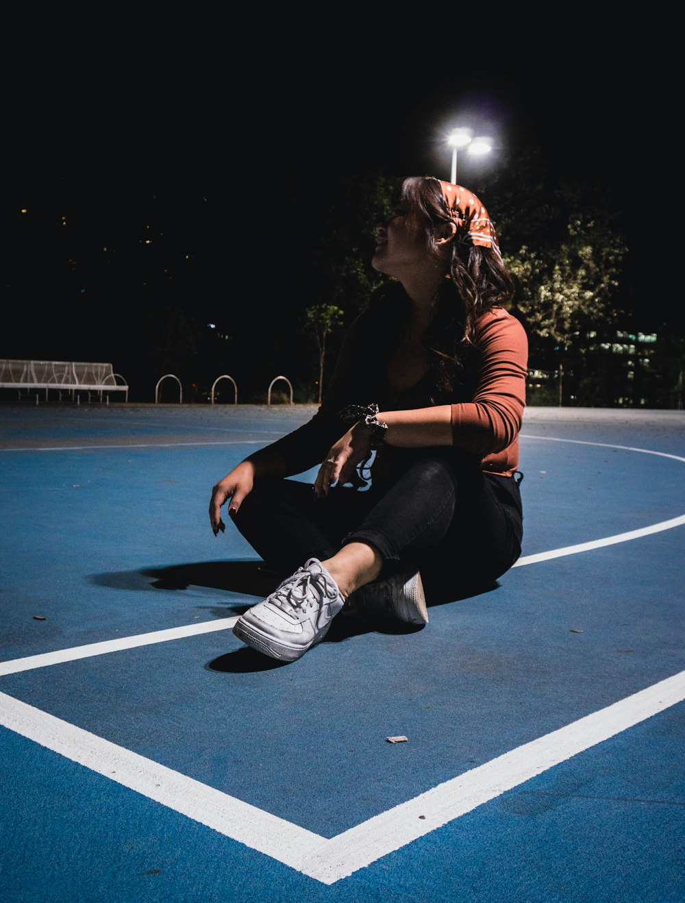 woman in black and white striped long sleeve shirt and black pants sitting on basketball court