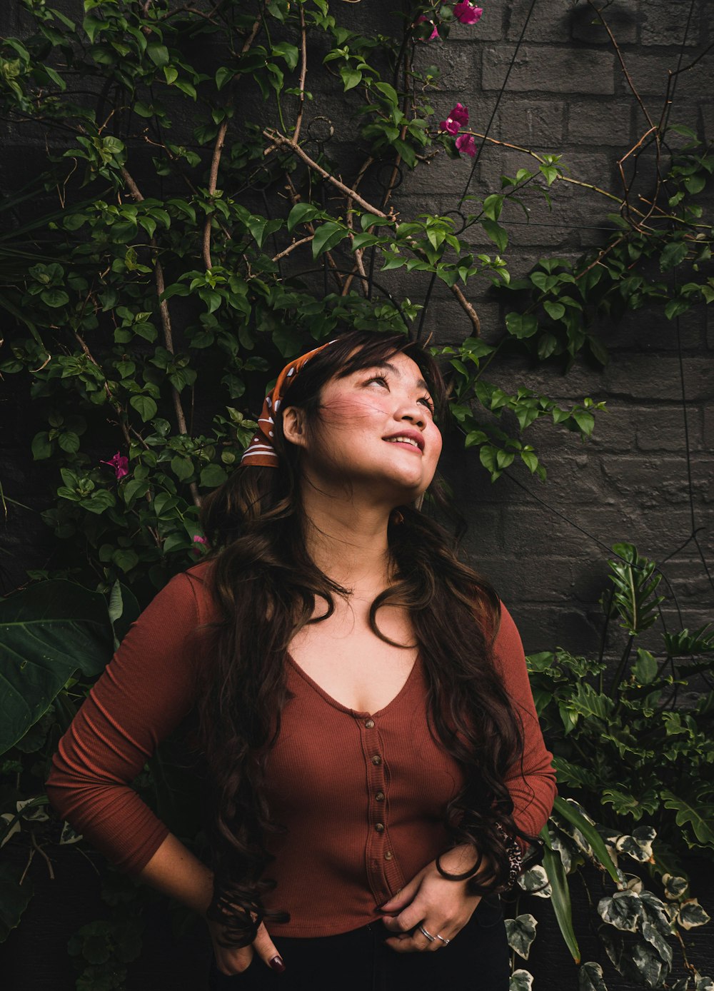 woman in red long sleeve shirt standing beside green plants