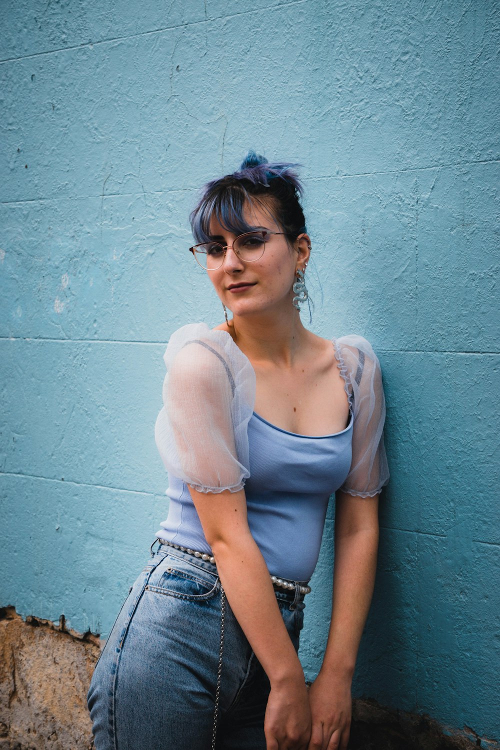 woman in white tank top and blue denim shorts sitting on concrete bench