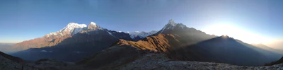 A panoramic view of majestic mountains under a clear blue sky, inviting adventure.