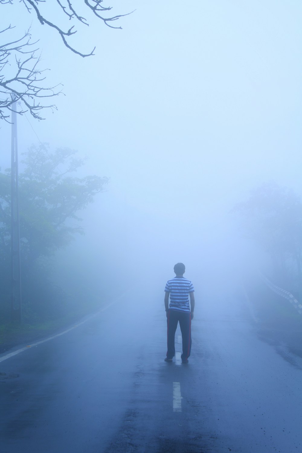 man in black jacket standing on foggy road