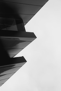 A sleek, modern architectural structure featuring sharp angles and clean lines in a monochromatic black and white palette.
