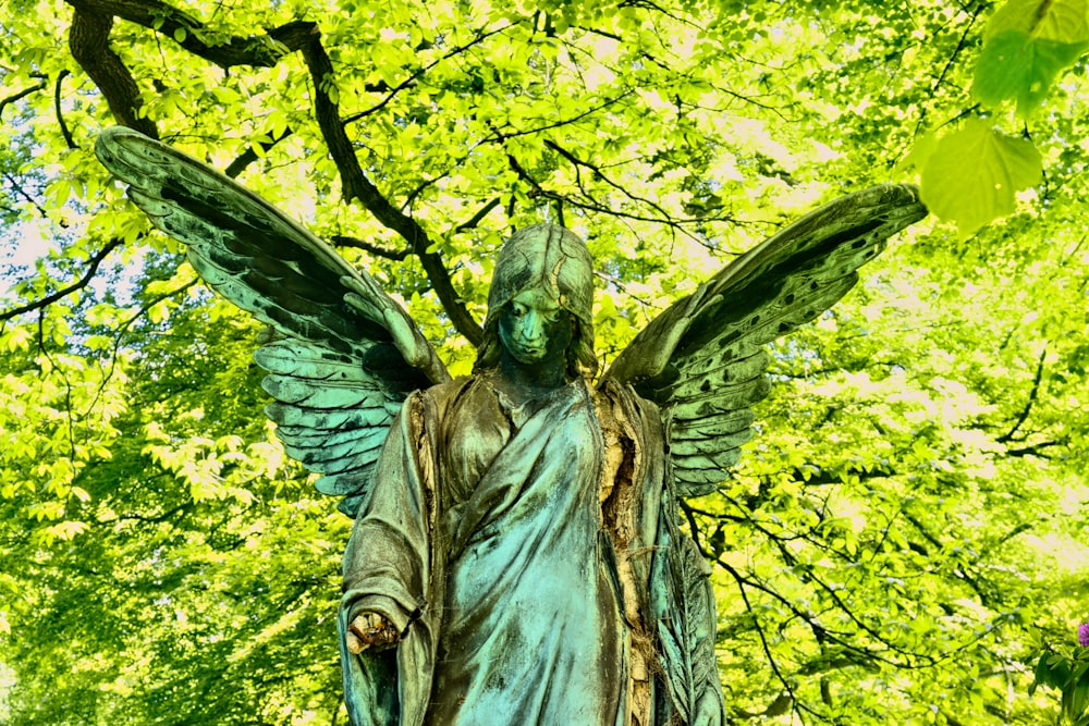 angel statue near green trees during daytime