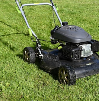 black and yellow push lawn mower on green grass during daytime