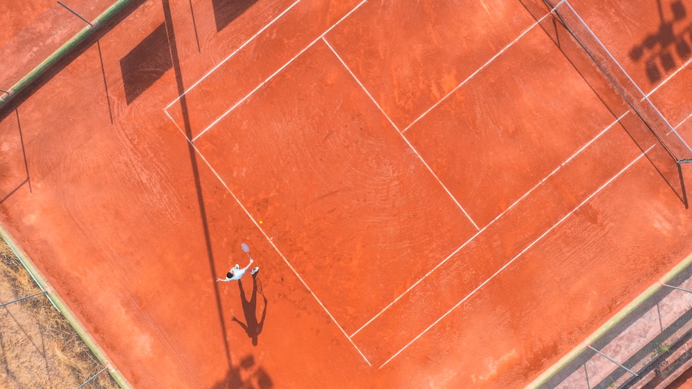 man in white shirt and black pants lying on orange floor tiles