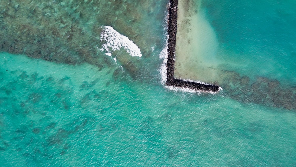 aerial view of white and black rock formation on body of water during daytime