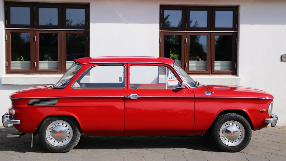 red car parked beside white building