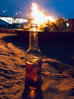 An elegant rose gold water bottle beside a cozy campfire under a starry night sky.