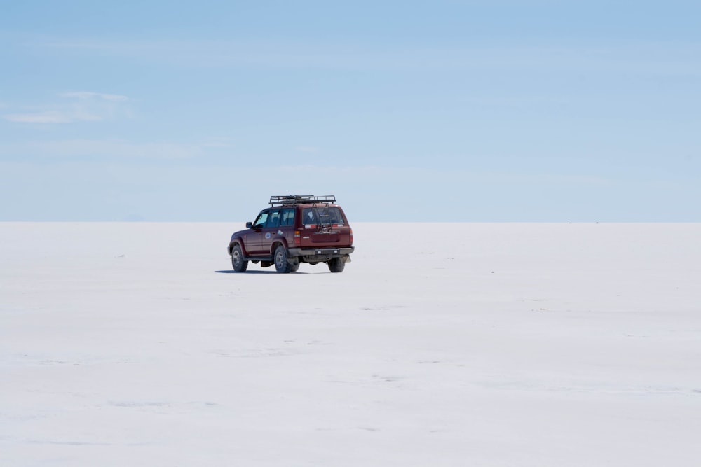 red suv on white sand during daytime