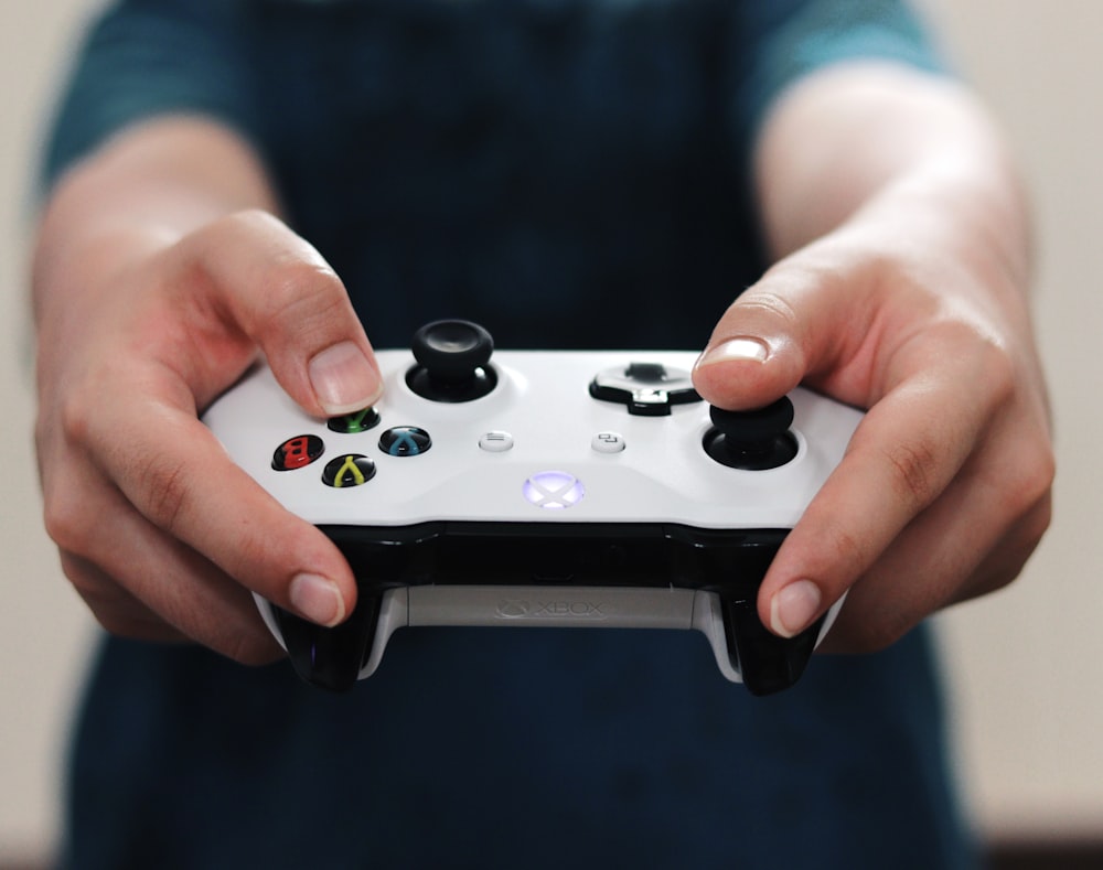 person holding white and black xbox one game controller