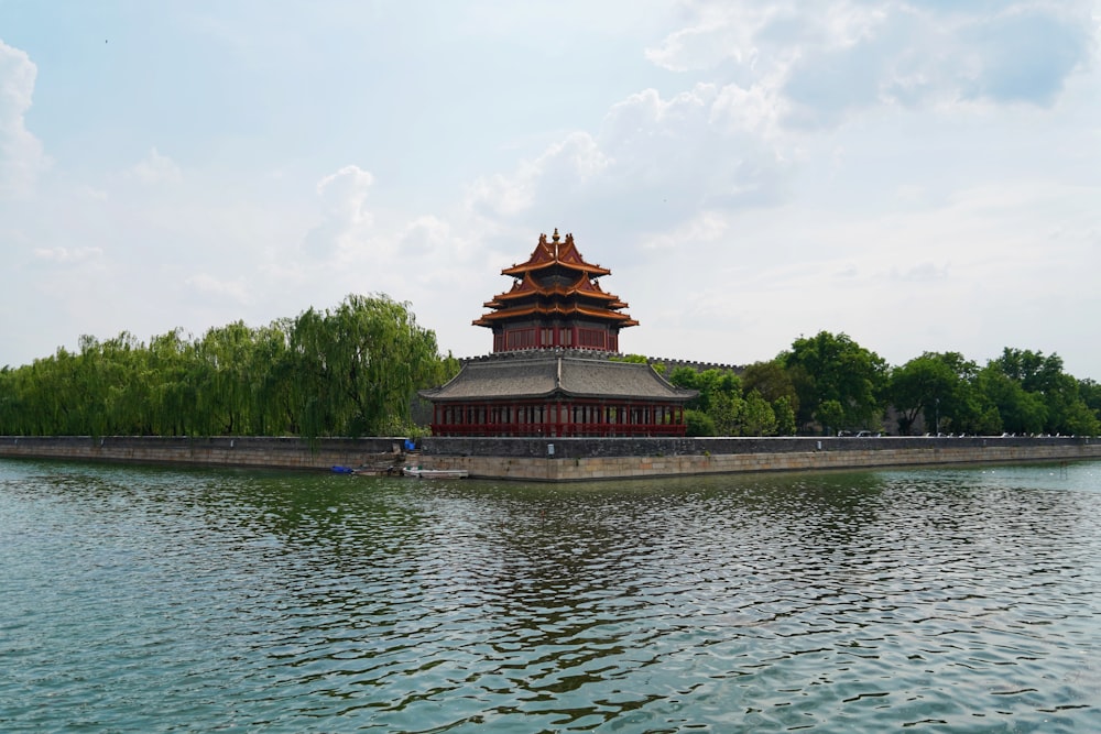 brown and green concrete building near body of water under white clouds during daytime