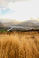 A sweeping aerial shot of a golden sunset over rolling hills and a winding river.