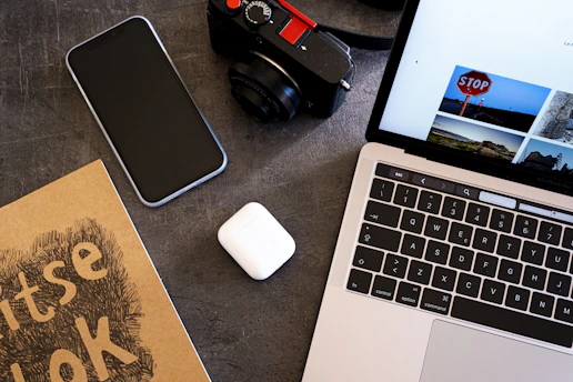 Flat-lay of a sleek desk setup with a laptop, smartphone, and tech accessories on a dark navy background.