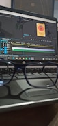 A pair of glasses is resting on a laptop keyboard. The laptop screen displays video editing software with a project timeline and a small image thumbnail labeled 'Sound On Podcast'.