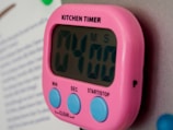A digital kitchen timer and thermometer placed beside a roasting pan.