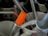A close-up of various kitchen utensils in a holder. There are metal spoons, forks, and a brush visible. A group of bright orange chopsticks stands out prominently among the utensils.