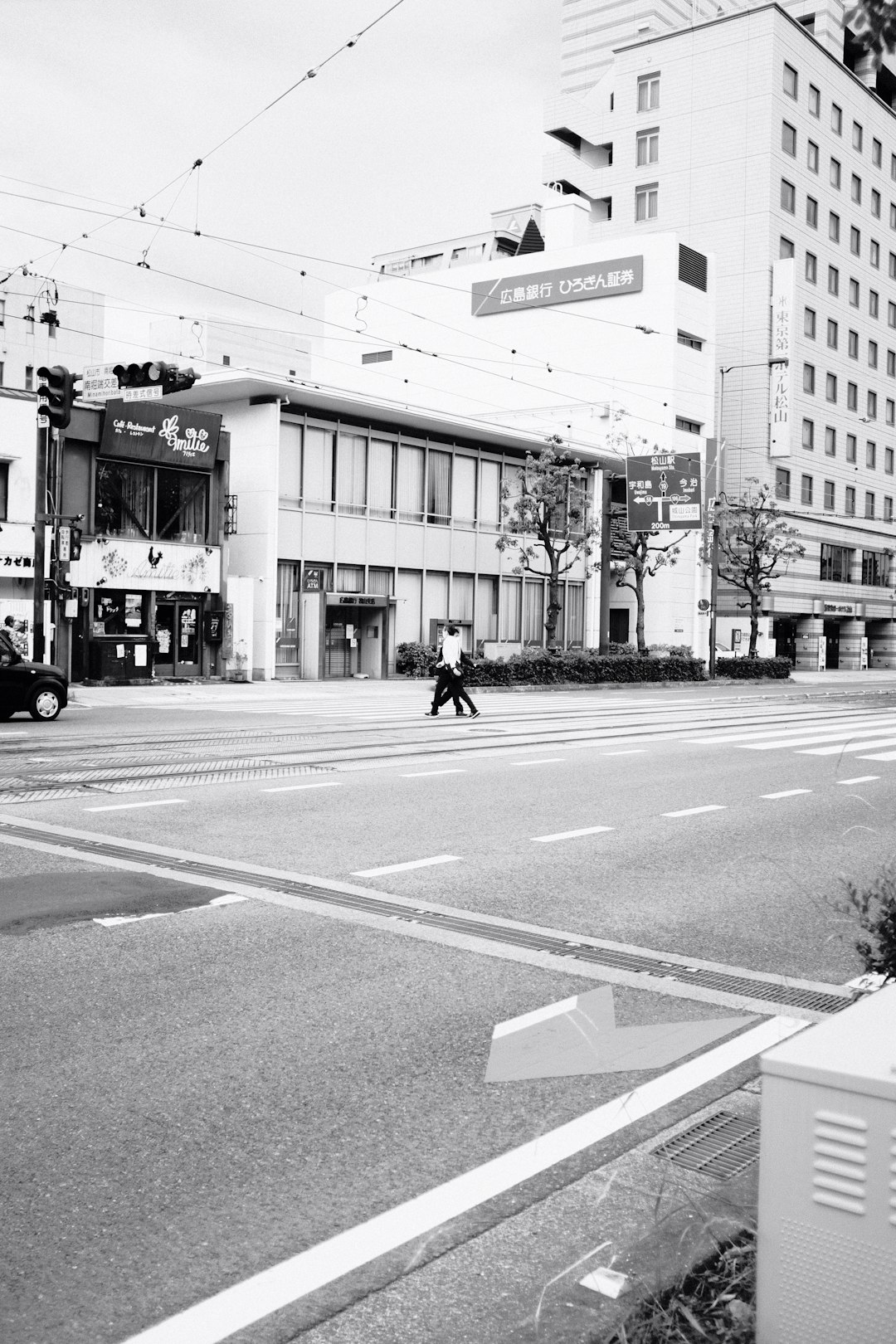 grayscale photo of man walking on pedestrian lane