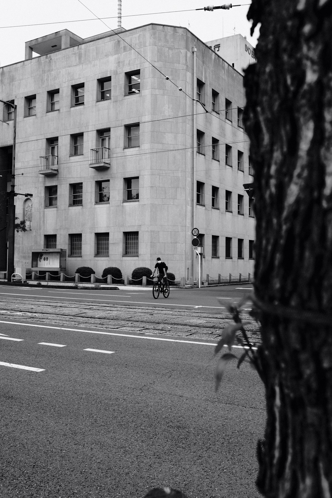 grayscale photo of man riding bicycle on road