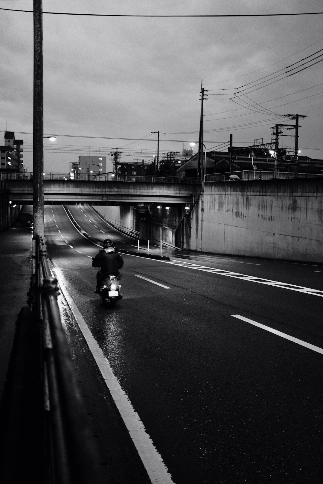 grayscale photo of man in black jacket riding motorcycle on road