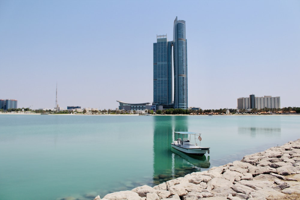 white and green boat on sea near city buildings during daytime