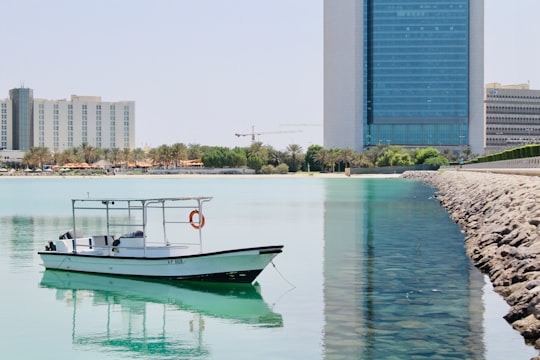 white and red boat on water near building during daytime in Corniche Beach - Abu Dhabi - United Arab Emirates United Arab Emirates