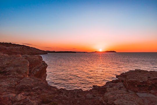brown rocky shore during sunset in Ibiza Spain