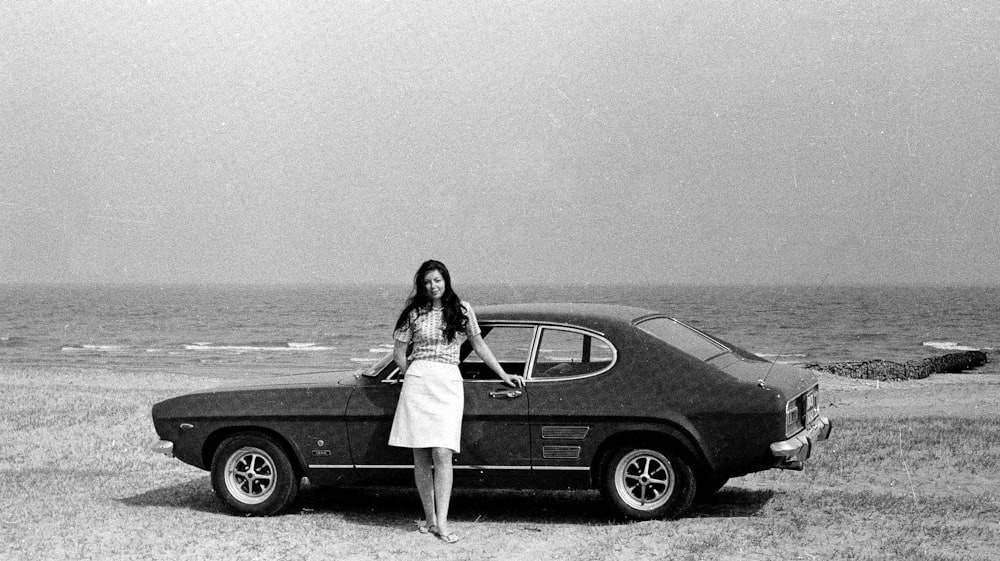 woman in white dress standing beside black car