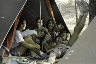 A lively group of travelers sharing laughs around a campfire on a group trip.