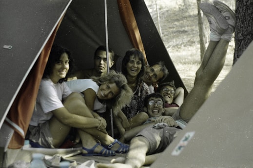 A lively group of travelers sharing laughs around a campfire on a group trip.