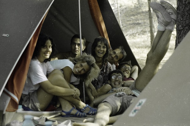Kids laughing inside a colorful tent during a forest camping trip at dusk.